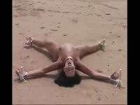 Humiliating bdsm video features tight bodied married woman secured to beach with stakes